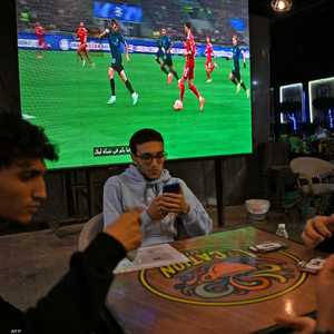 يجلس الزبائن في المقهى بعضهم منشغل أثناء مباراة ليفربول