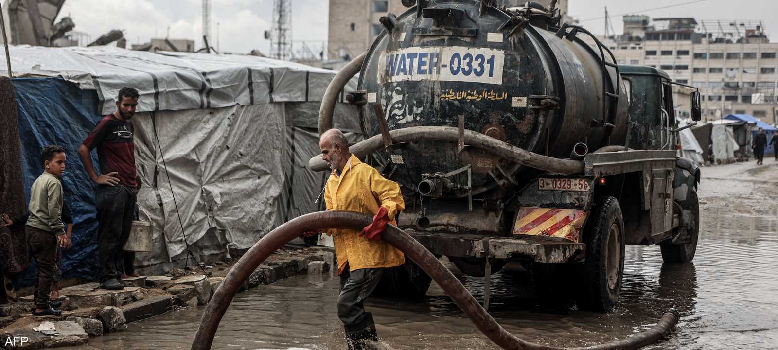 عامل من بلدية غزة يسحب مياه الأمطار التي أغرقت الشوارع