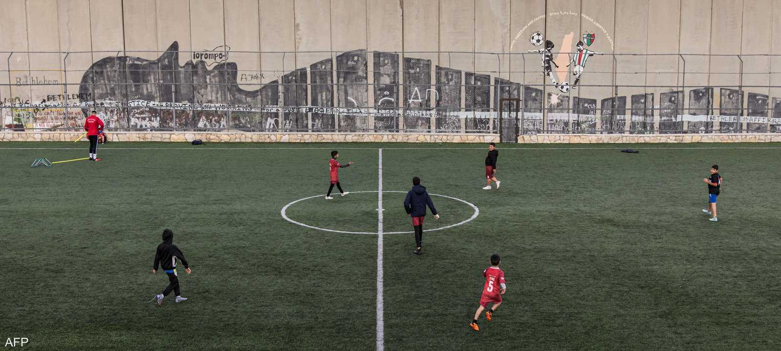 الملعب ملاصق للجدار الذي بنته إسرائيل لعزل الضفة
