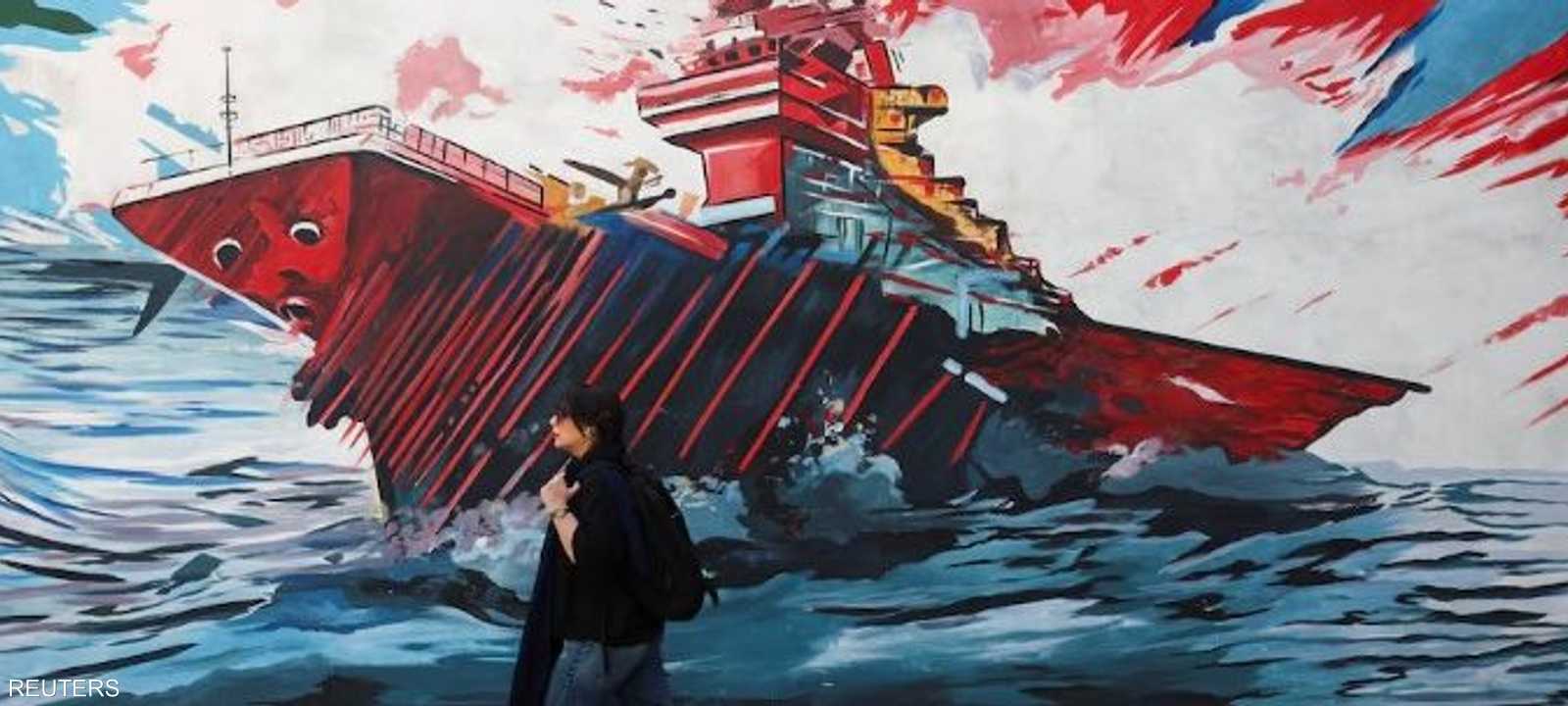 سيدة إيرانية تسير بجانب لوحة جدارية مناهضة لأميركا في طهران