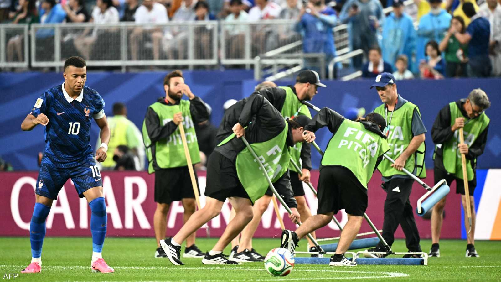 فريق يقوم بتنظيف الملعب بعد هطول أمطار غزيرة.