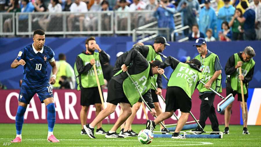 فريق يقوم بتنظيف الملعب بعد هطول أمطار غزيرة.