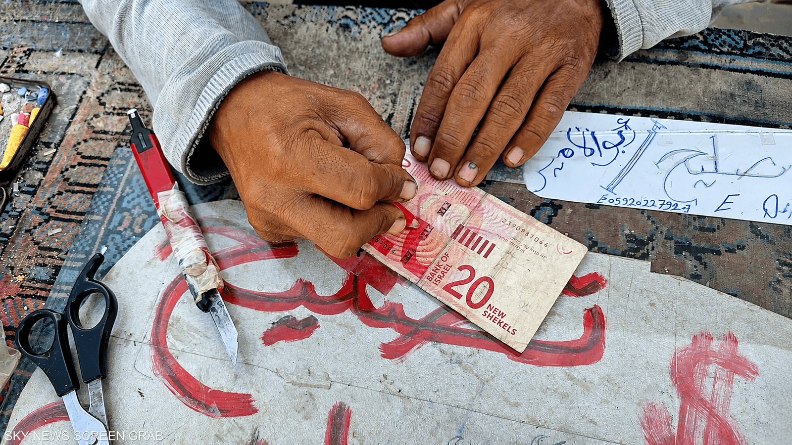 فلسطيني يصلح ورقة نقدية مهترئة