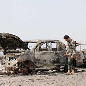 مقاتل في الحزام الأمني يتفقد مركبا عسكرية محترقة للإخوان