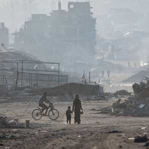 فلسطينيون يسيرون وسط أنقاض المباني المدمرة في مدينة غزة